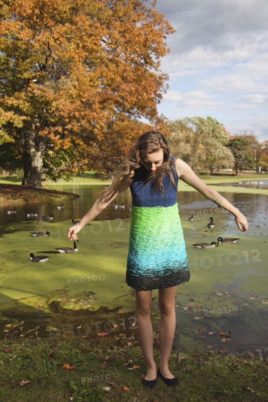 Woman wearing dress near duck pond in park