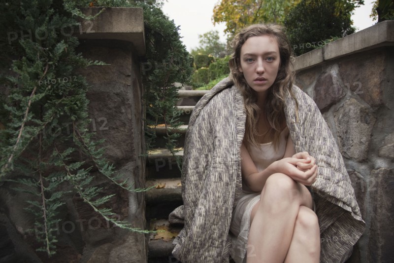Woman wrapped in blanket sitting on stone steps
