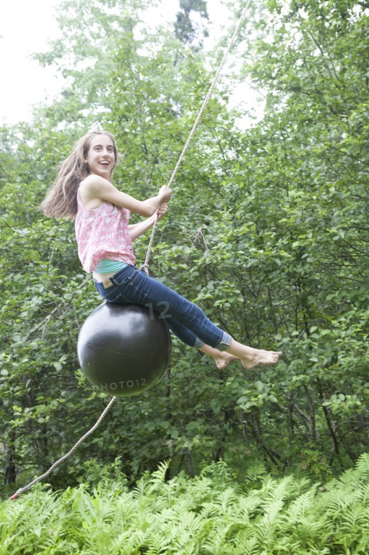 Teenage girl swinging on rope swing