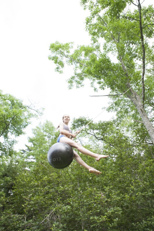 Teenage girl swinging on rope swing