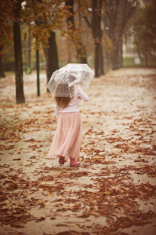 Caucasian girl carrying umbrella in park