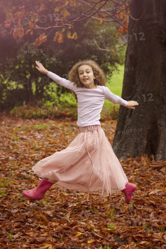Caucasian girl jumping for joy in autumn leaves
