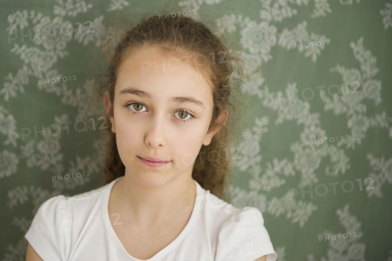 Close up of somber Caucasian girl near wallpaper