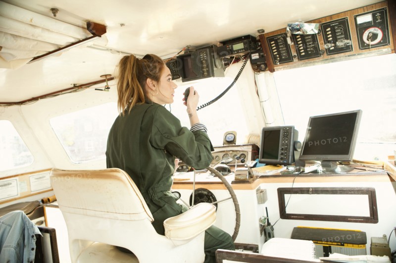 Woman using walkie-talkie and steering boat