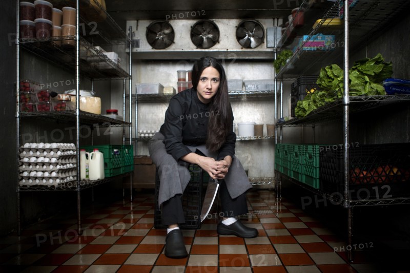 Chef sitting in walk-in refrigerator in restaurant