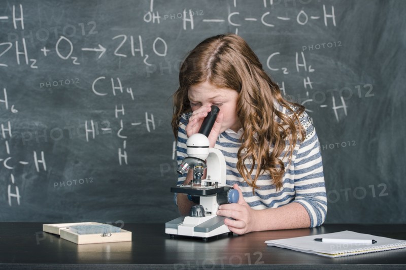 Caucasian student using microscope in science class