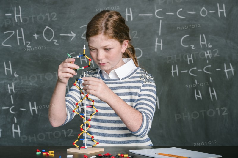 Caucasian student examining molecular model in science class