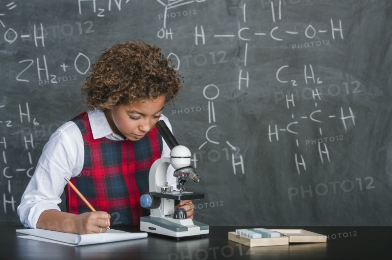Mixed race student using microscope in science class