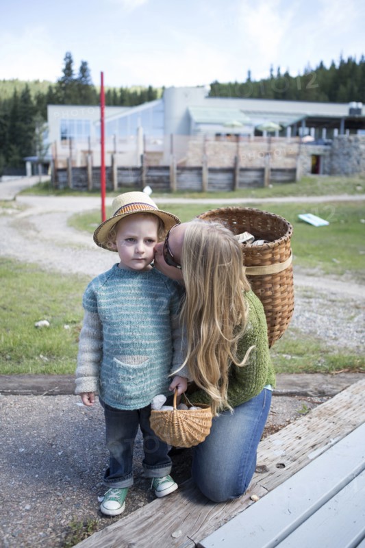Mother with long hair kissing son in park