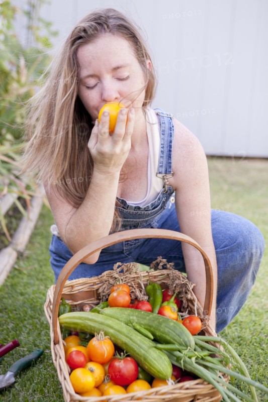 Mixed race farmer smelling vegetables in garden