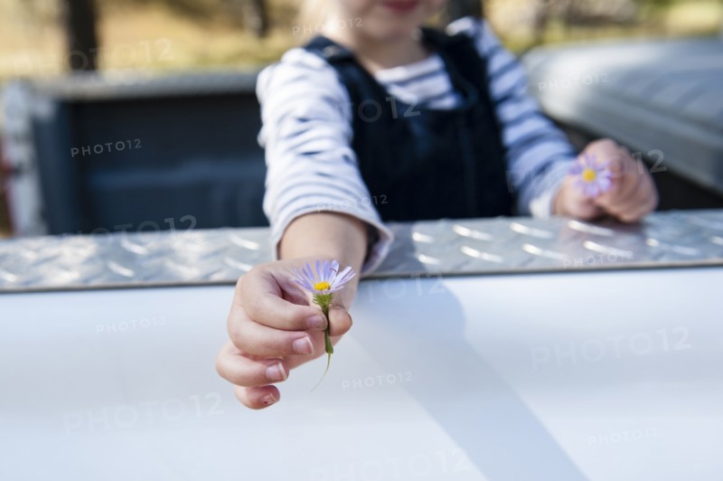 Caucasian girl holding flowers in truck bed