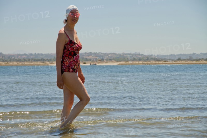 Caucasian woman walking in waves on beach