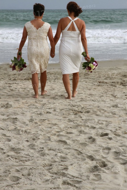 Lesbian brides holding hands on beach