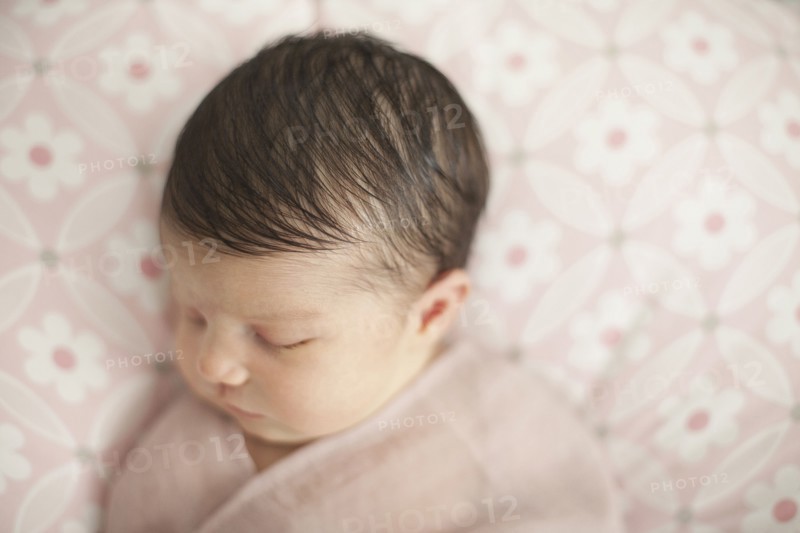 Caucasian baby girl swaddled in blanket