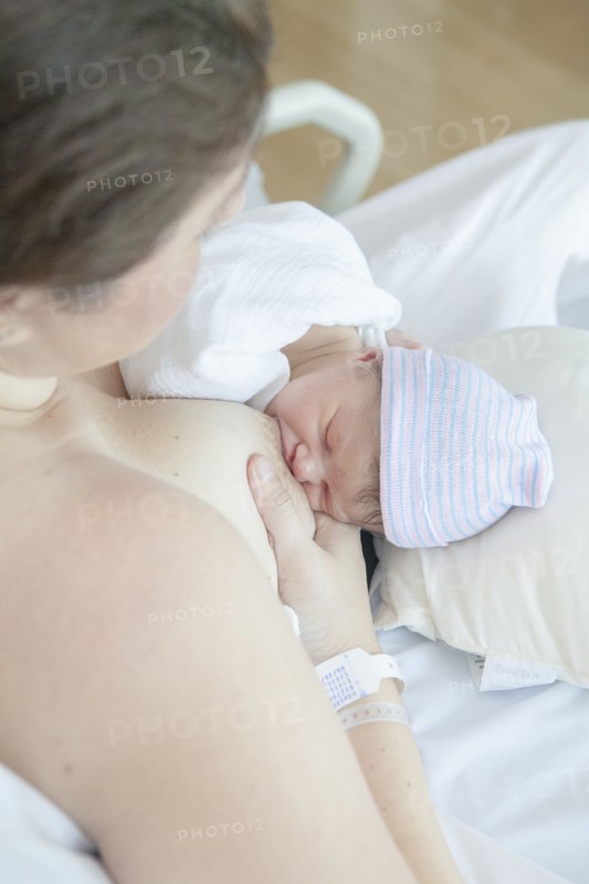 Caucasian mother nursing newborn daughter in hospital bed