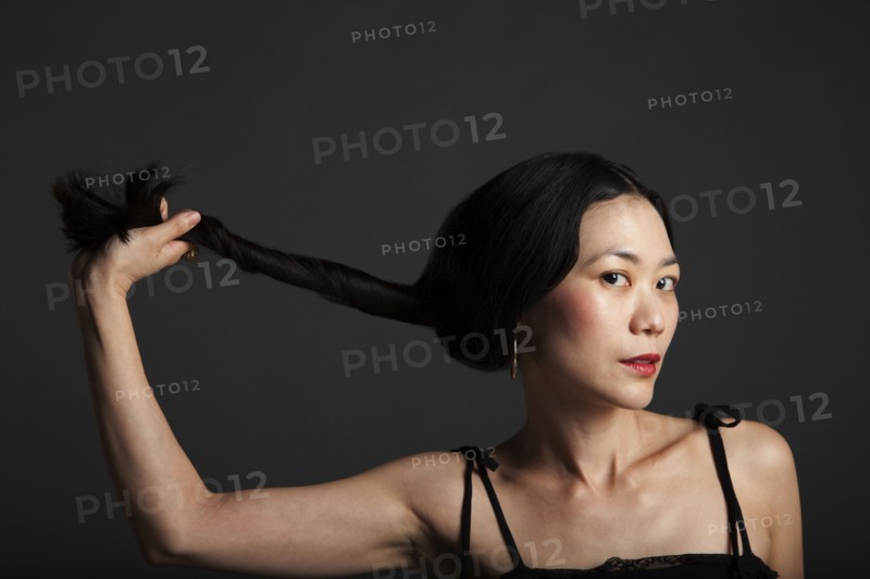Asian woman twisting her hair in ponytail