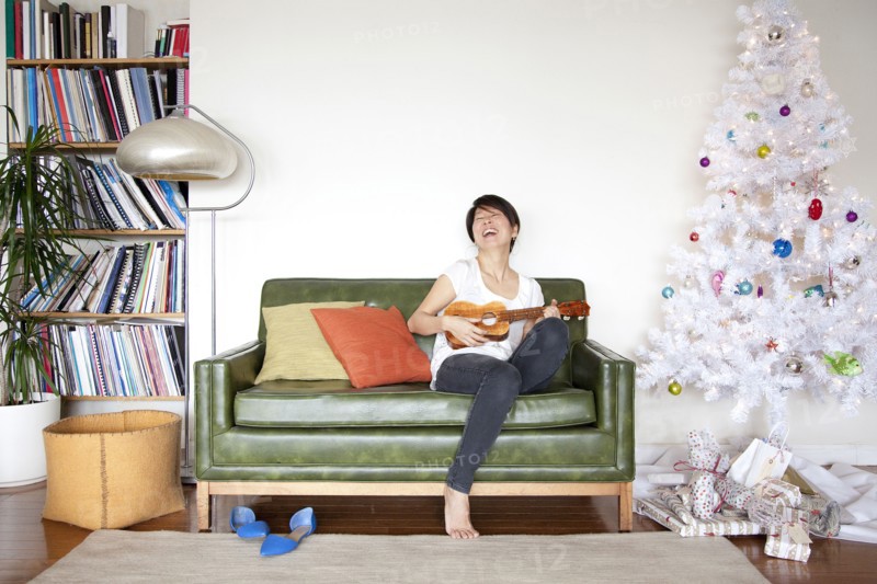Japanese woman playing ukulele near Christmas tree