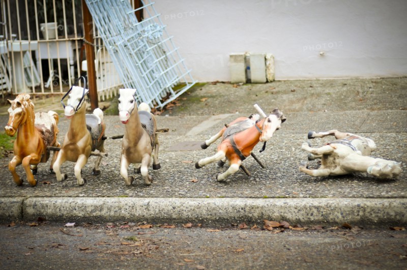 Toy rocking horses on city sidewalk