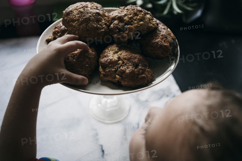 Girl reaching for cookie on kitchen counter