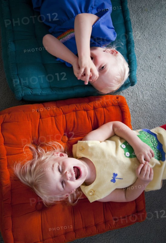 Brother and sister playing on cushions on floor