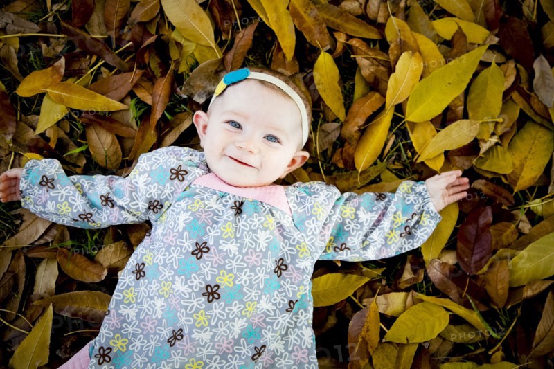 Mixed race baby girl laying in autumn leaves