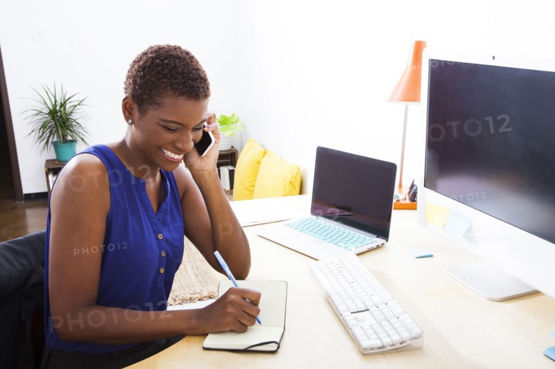 Black businesswoman talking on cell phone at office desk