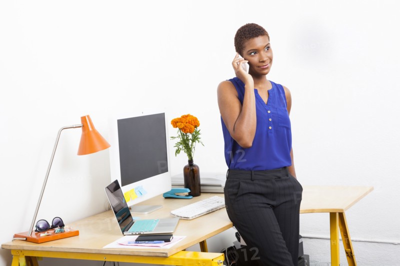 Black businesswoman talking on cell phone at office desk