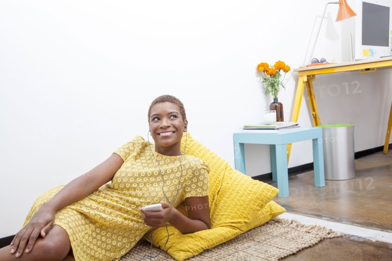 Black woman listening to mp3 player on floor