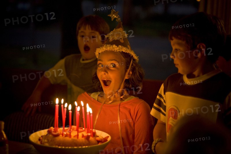Laughing girl blowing candles on birthday cake