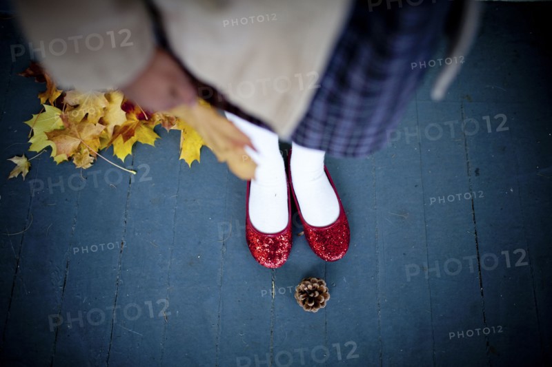 Girl wearing red slippers near pinecone
