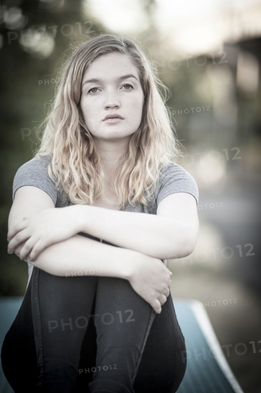 Serious woman hugging her knees