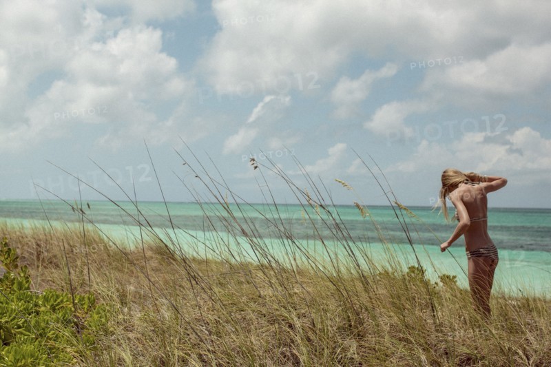Woman in bikini standing in beach grass