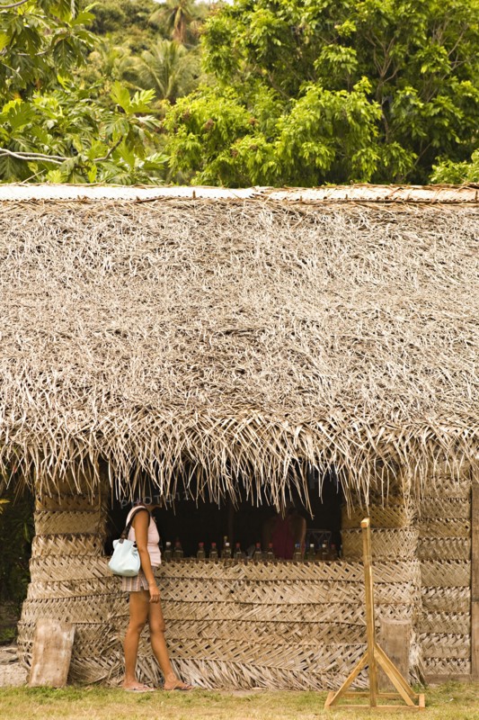 Woman standing under thatched hut roof