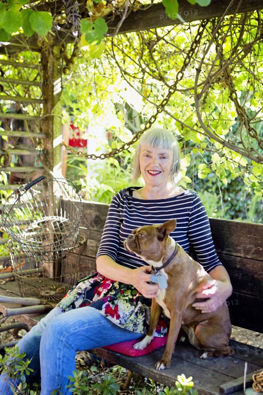 Older Caucasian woman petting dog in garden