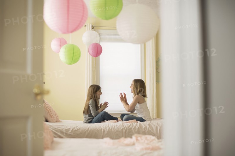 Caucasian girls playing clapping game in bedroom