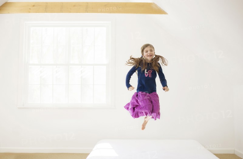 Caucasian girl jumping on bed
