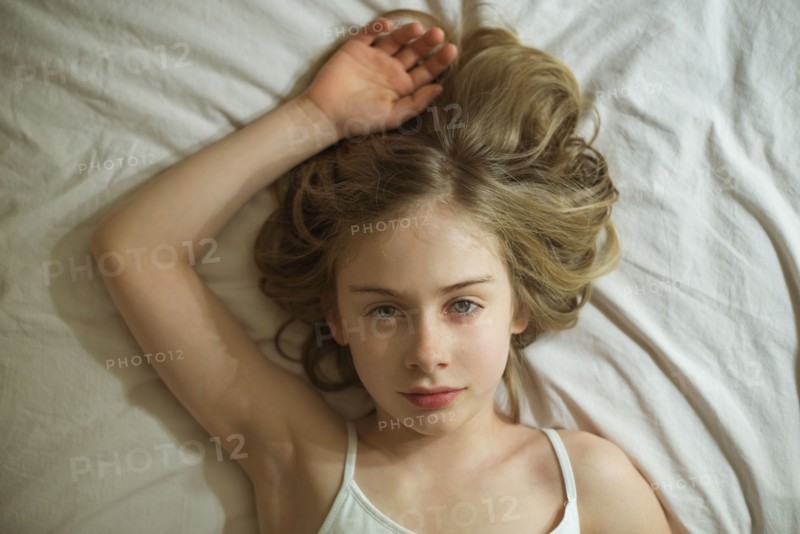 Serious Caucasian girl laying on bed