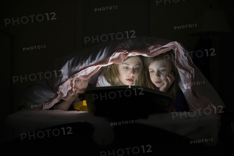 Caucasian sisters using laptop in blanket fort night
