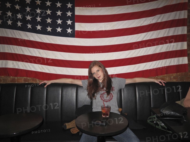Caucasian woman sitting under American flag in restaurant