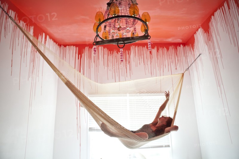 Caucasian woman laying in hammock under dripping ceiling