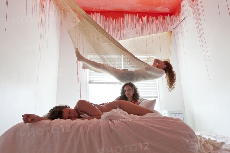 Women laying on bed and hammock under dripping ceiling