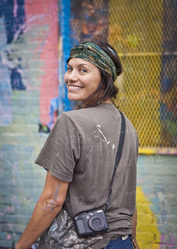Caucasian woman with paint-splattered shirt smiling