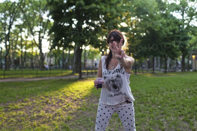 Caucasian woman gesturing peace sign in park