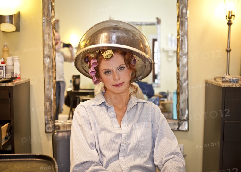 Woman sitting under hair dryer in salon