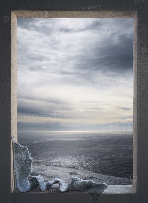 Knitted scarf in window over seascape