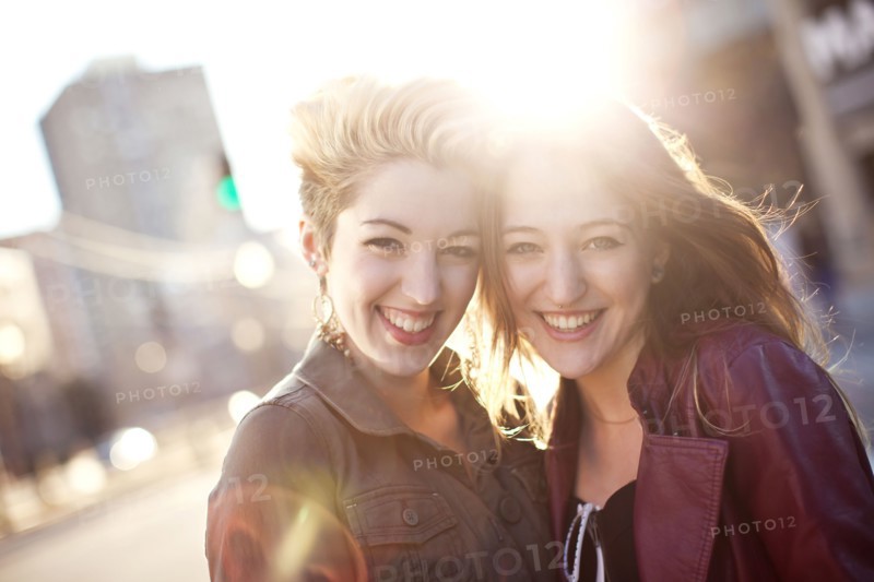 Women hugging on sunny city sidewalk