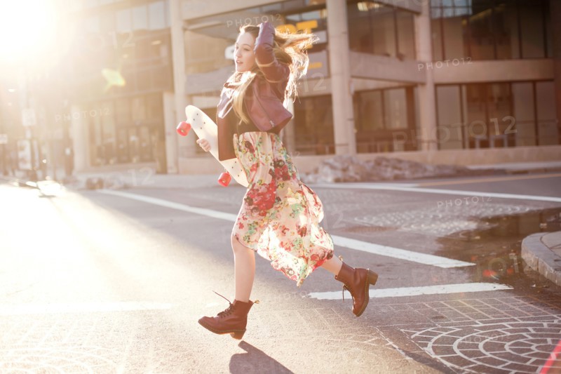 Woman carrying skateboard in city intersection
