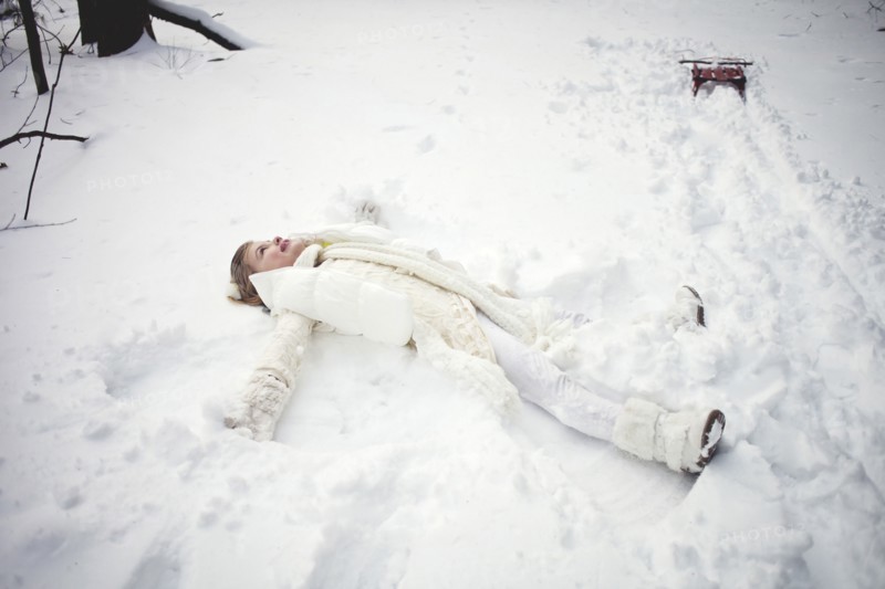 Caucasian girl making snow angel in field