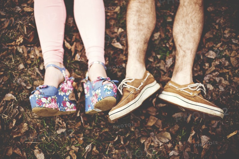 Close up of shoes of couple laying in autumn leaves