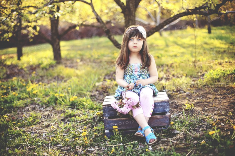 Girl sitting on crate in orchard